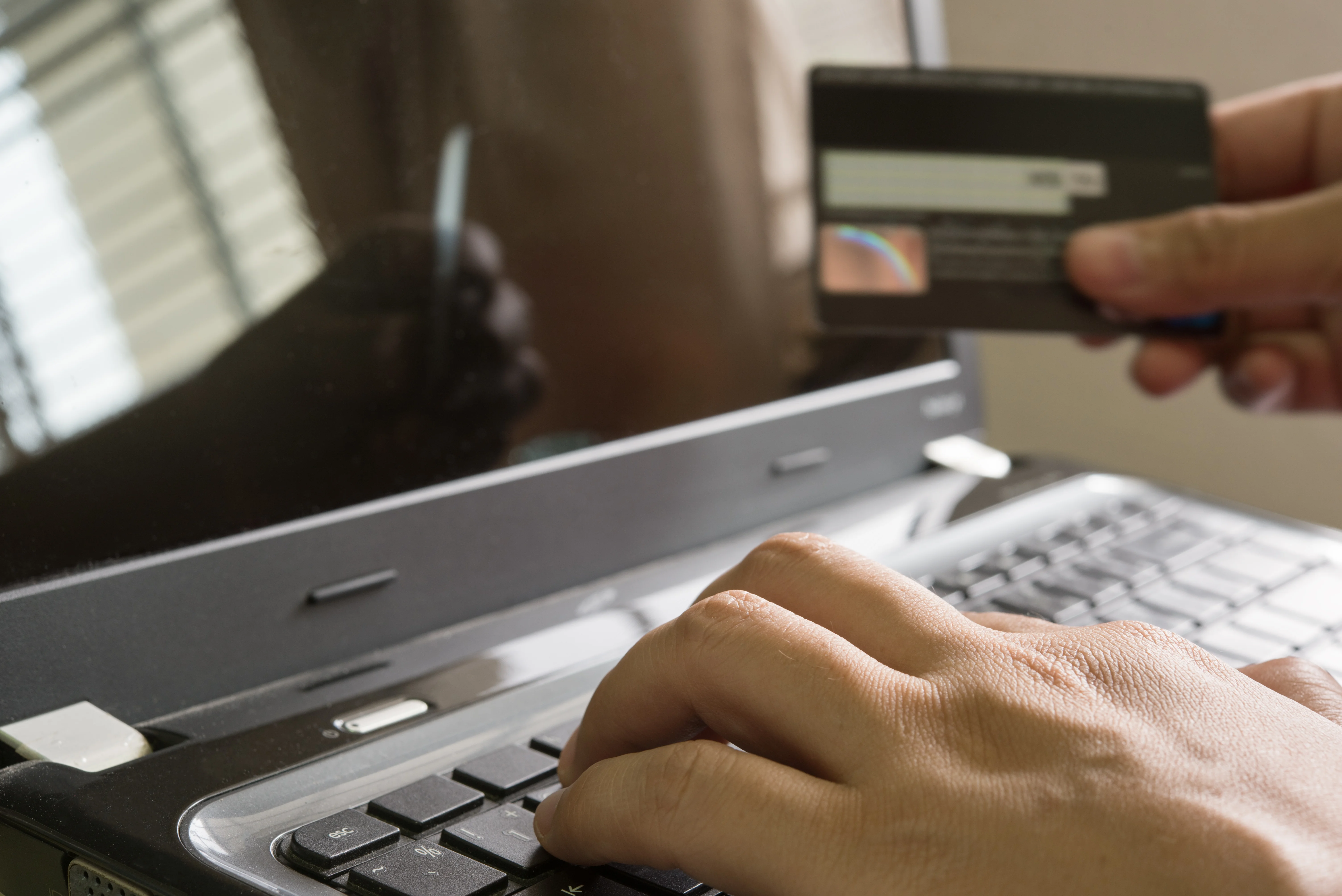 hand-holding-credit-card-using-laptop.webp